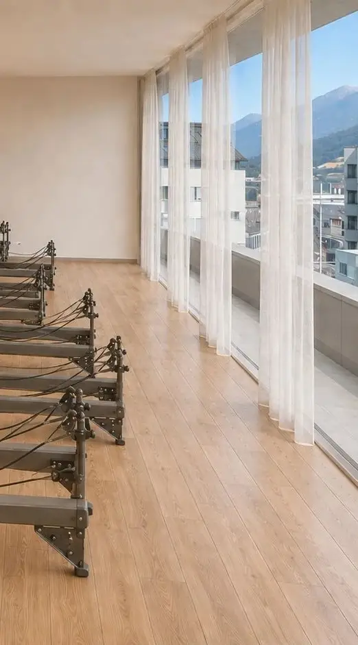 Der Reformer-Raum von ella in Innsbruck: bodentiefe Fenster mit Blick auf die Berge, Eichenboden, Reformer in Reihen